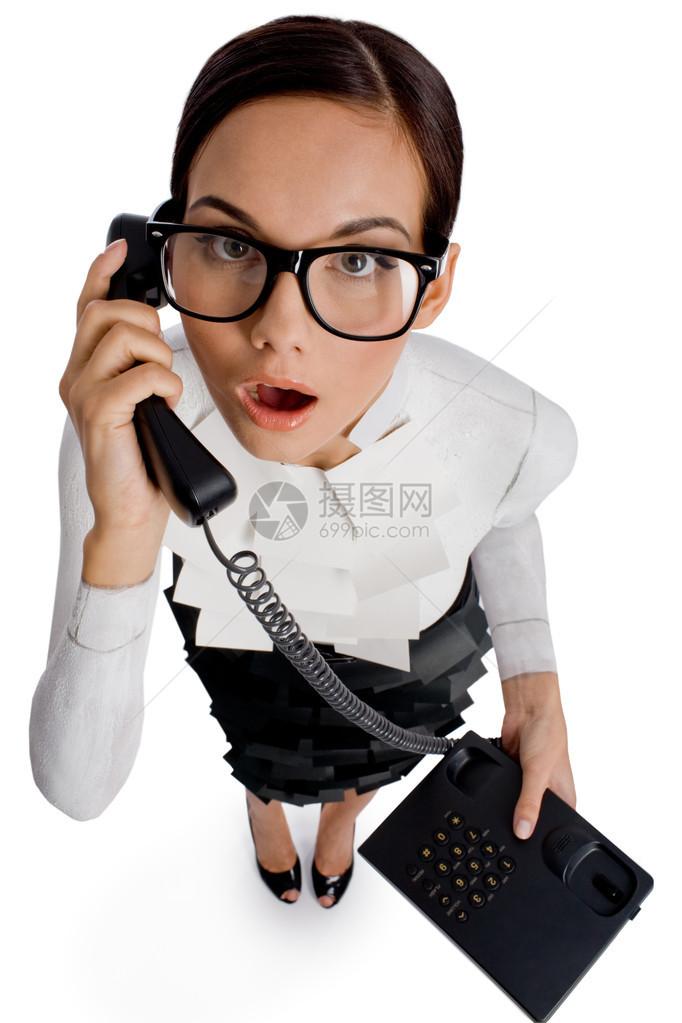 戴着眼镜的惊讶女人在电话里说话看着相机图片