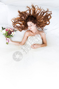 穿着白礼服的新娘用花束睡在图片