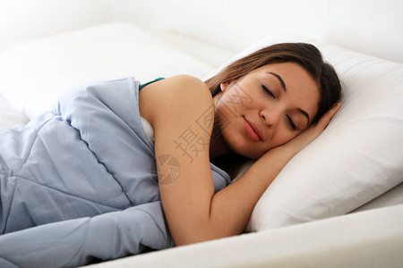 美丽的年轻女士睡在舒适和幸福的床上睡觉图片