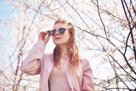 戴着太阳镜的女孩站在樱花树下图片