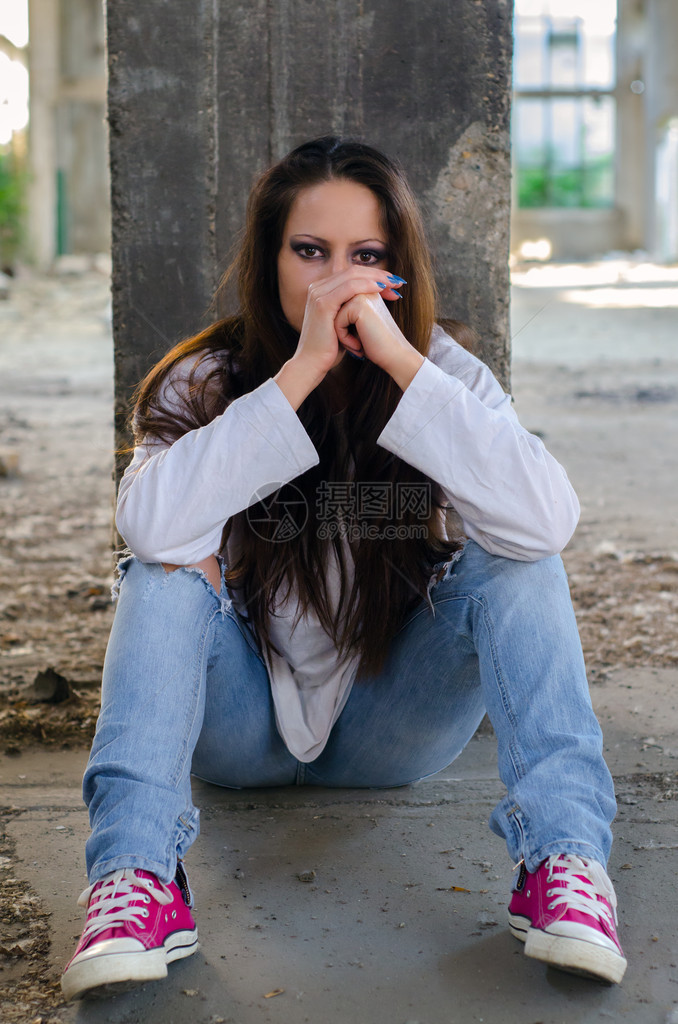坐在废弃大楼水泥地板上的年轻压抑的女图片