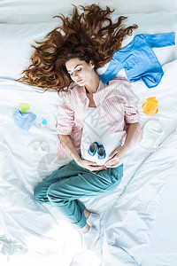 孕妇睡在婴儿衣着中的床上最图片