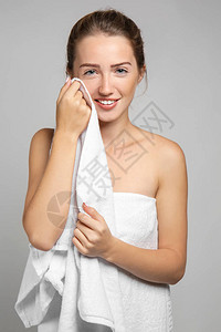美丽的年轻女子洗完澡后用毛巾擦脸灰图片