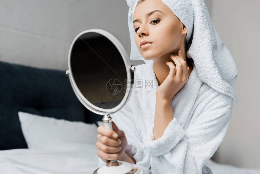 穿着白浴袍和毛巾的年轻女子在镜子里图片
