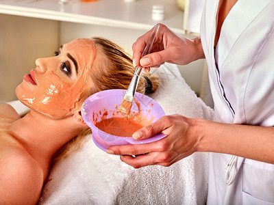 眼镜面罩皮肤畸形治疗美容院接受化妆手术的妇女背景上含润湿奶油的瓶子图片