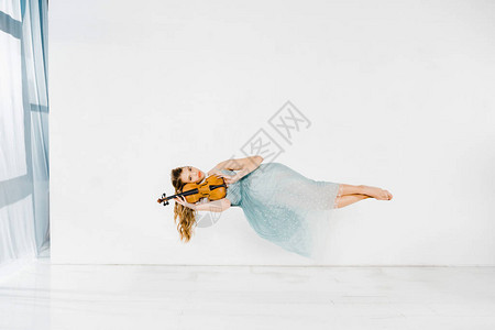 穿着蓝裙子的女孩拿着小提琴在空气中图片