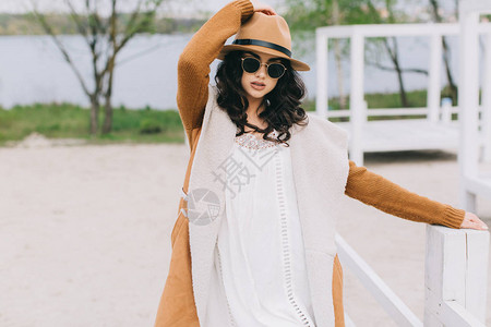 穿着棕色帽子的漂亮模特穿着嬉皮风格的白礼服在夏图片