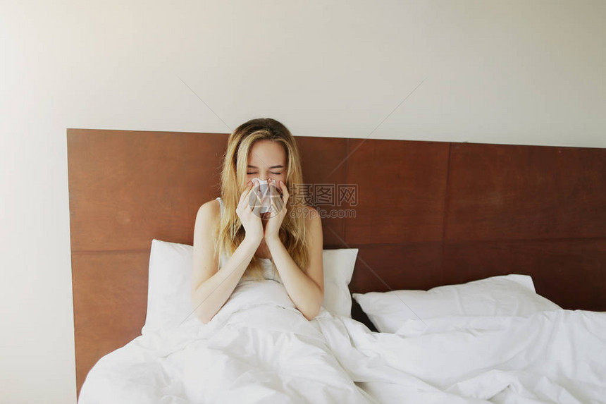 女病人在白床上打喷嚏时用餐巾纸擦亮阳光图片
