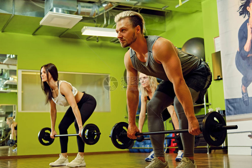运动的金发男人和两个女人在健身房图片