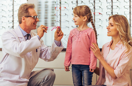 好小女孩和她的母亲在眼科医生咨询英俊的中年医生图片