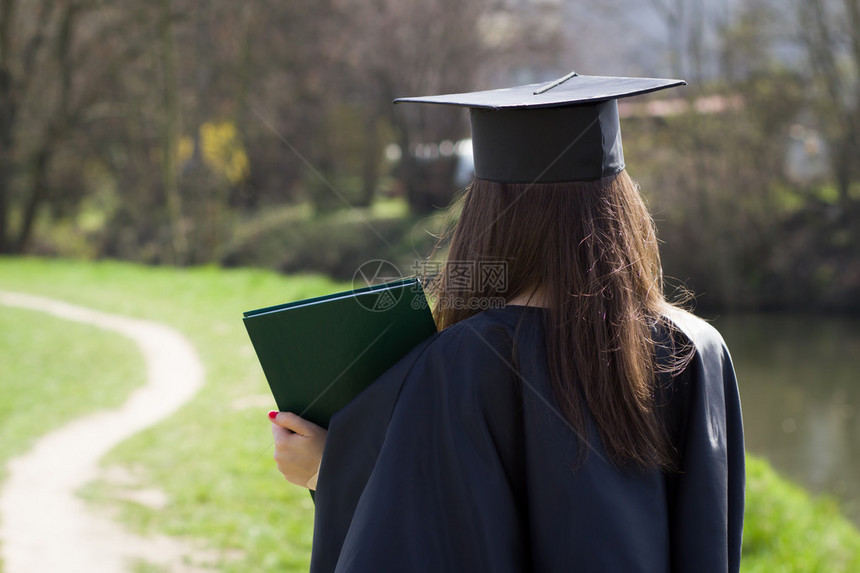 相当聪明的大学生毕业后的女孩完成仪式穿着长袍和灰泥板图片