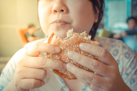 亚洲女胖的身体吃汉堡包是一种不健康的快餐食品图片