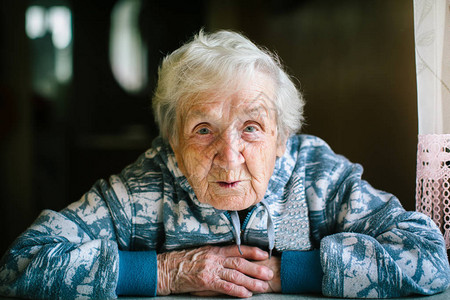 坐在桌子旁的房子里的老年妇女图片