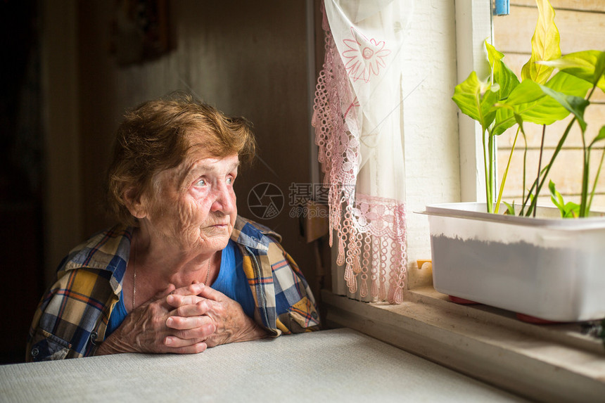 忧郁的老妇人望着窗外图片