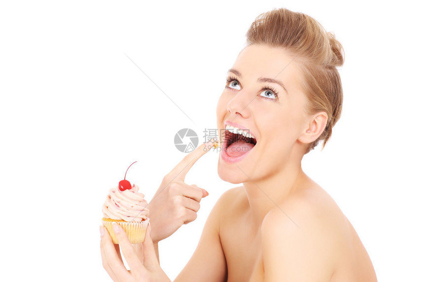 一张年轻快乐的女青年的照片带着一个纸杯蛋糕在白图片