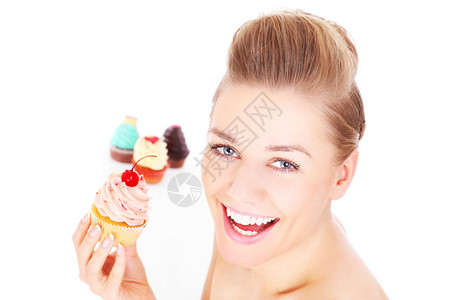 一张年轻快乐的女青年的照片带着一个纸杯蛋糕在白背景图片