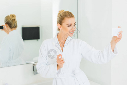 白浴袍中美丽的女人有选择焦点拿着牙刷图片