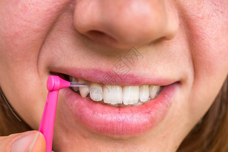 用齿间刷牙的女人牙科护理概念图片
