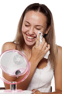 年轻微笑的女人用湿纸巾清洁她的脸图片