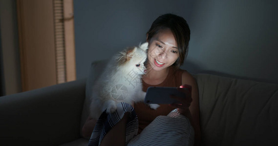 女人晚上和她的小狗一起看手机图片
