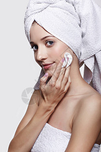 化妆垫的漂亮女孩的画像头上有浴巾的年轻女子女穿着浴巾在灰色的图片