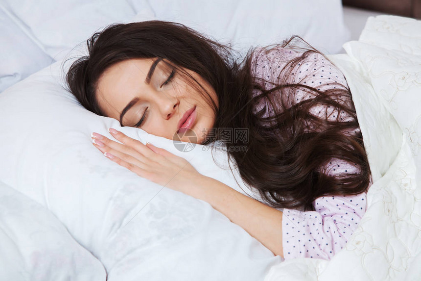 女孩睡在家里的一张白色床上年轻女子穿着睡衣在家里床上的白色床图片