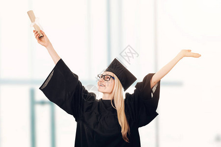穿着帽子和长袍并持有毕业证书的快乐大学毕业生身着图片