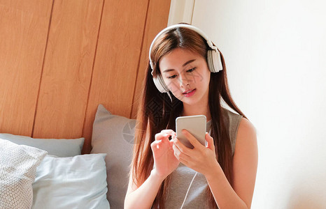 亚洲美丽可爱的女士拥有手机和耳机听图片