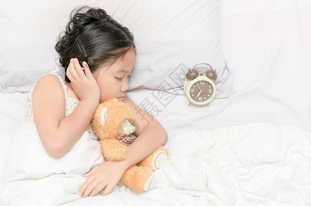 可爱女孩睡觉拥抱泰迪熊娃和闹图片
