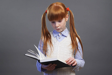穿蓝衬衫的红发美女和穿着两匹马尾辫的白色背心正在阅读一本书图片