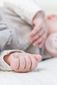 睡在白色床罩上的带奶嘴的女婴手特写图片