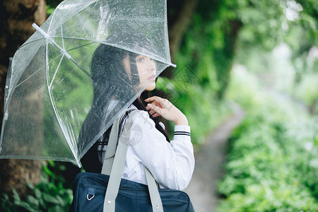 下雨时在自然行走道上带着雨伞走路的亚图片