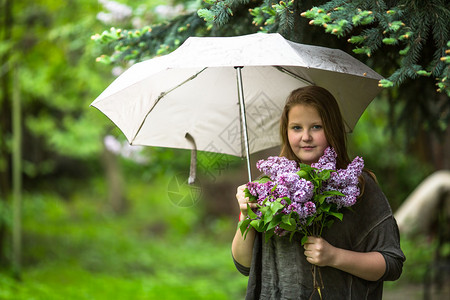带着一束花的少女站在花园的雨伞图片