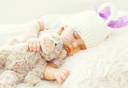 可爱的婴儿睡觉与泰迪熊玩具在家中一个图片