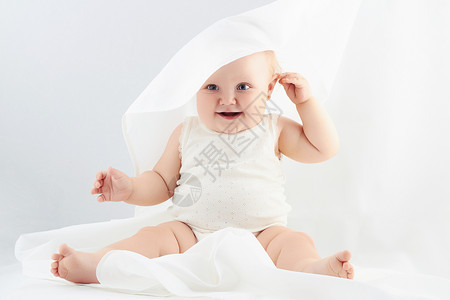 在白毯下笑着的女婴图片