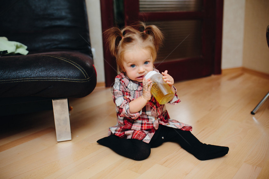 可爱的女婴坐在地板上喝茶图片