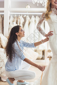 美丽的新娘和女裁缝在婚纱沙图片