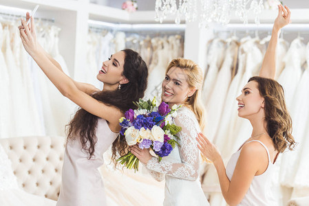 年轻笑的新娘带着花束和伴娘在婚礼时图片