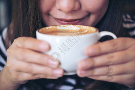 亚洲女在白杯中闻着喝热咖啡在咖啡馆感图片