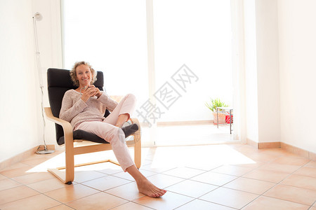 有吸引力的成熟健康的女人坐在家里舒适的扶手椅上放松图片