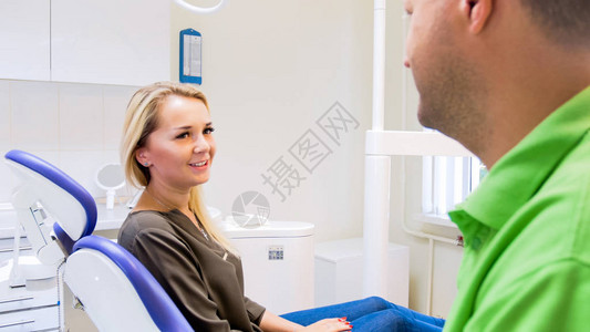 坐在牙科椅上向牙医微笑的美丽的图片
