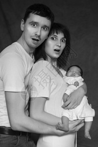 小婴儿男婴睡在母亲和父亲的手臂上爸妈吓坏了中黑色背景图片