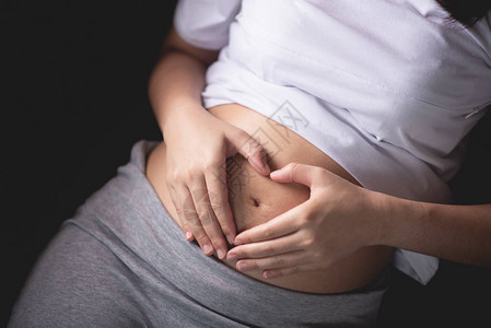 孕妇将手握在肚子肿胀的肚子上图片