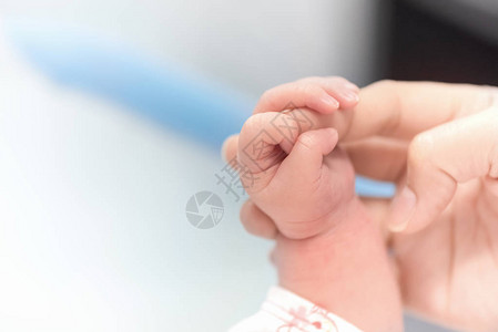 新生儿手握母亲手指在医院婴儿和保健概念选择焦点和白色小插图复图片