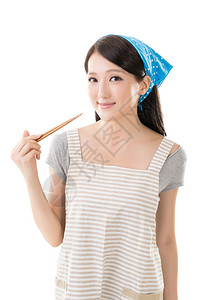 年轻的亚洲家庭主妇在围裙上握着筷子在白色背图片