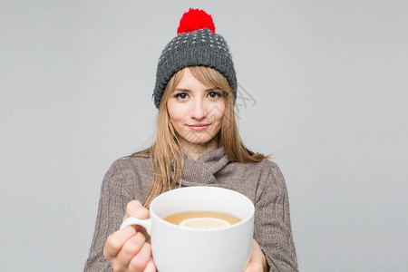 穿着编织帽的年轻美女喝着大白杯茶背景图片