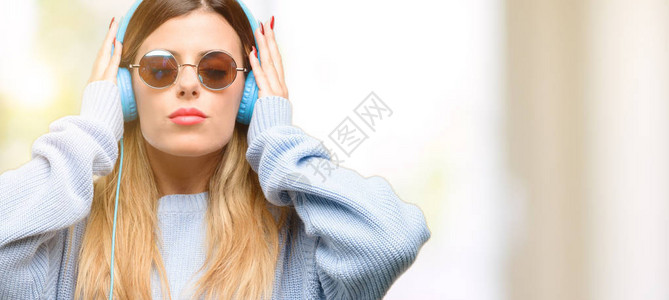 年轻女子用耳机盖住耳朵听音乐图片