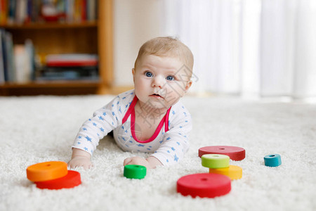 可爱的新生婴儿在白色背景上玩彩色木制拨浪鼓玩具球背景图片