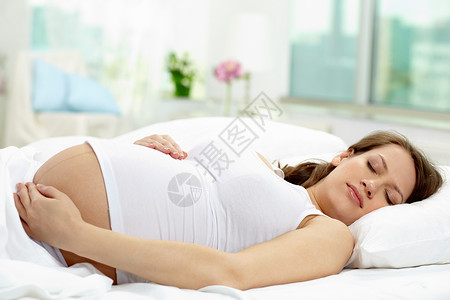 美丽的孕妇在床上睡觉的照片图片