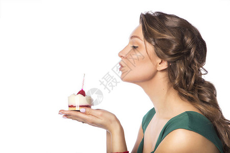 穿着绿色节庆礼服在生日晚会蛋糕上吹蜡烛的黑人女子白种背景与世隔图片